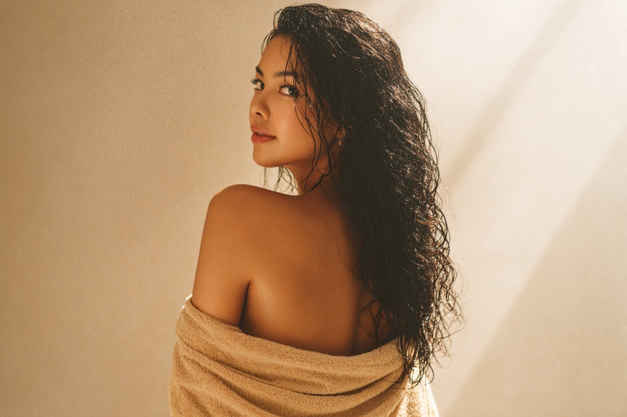 Woman wrapped in a beige towel against a neutral background