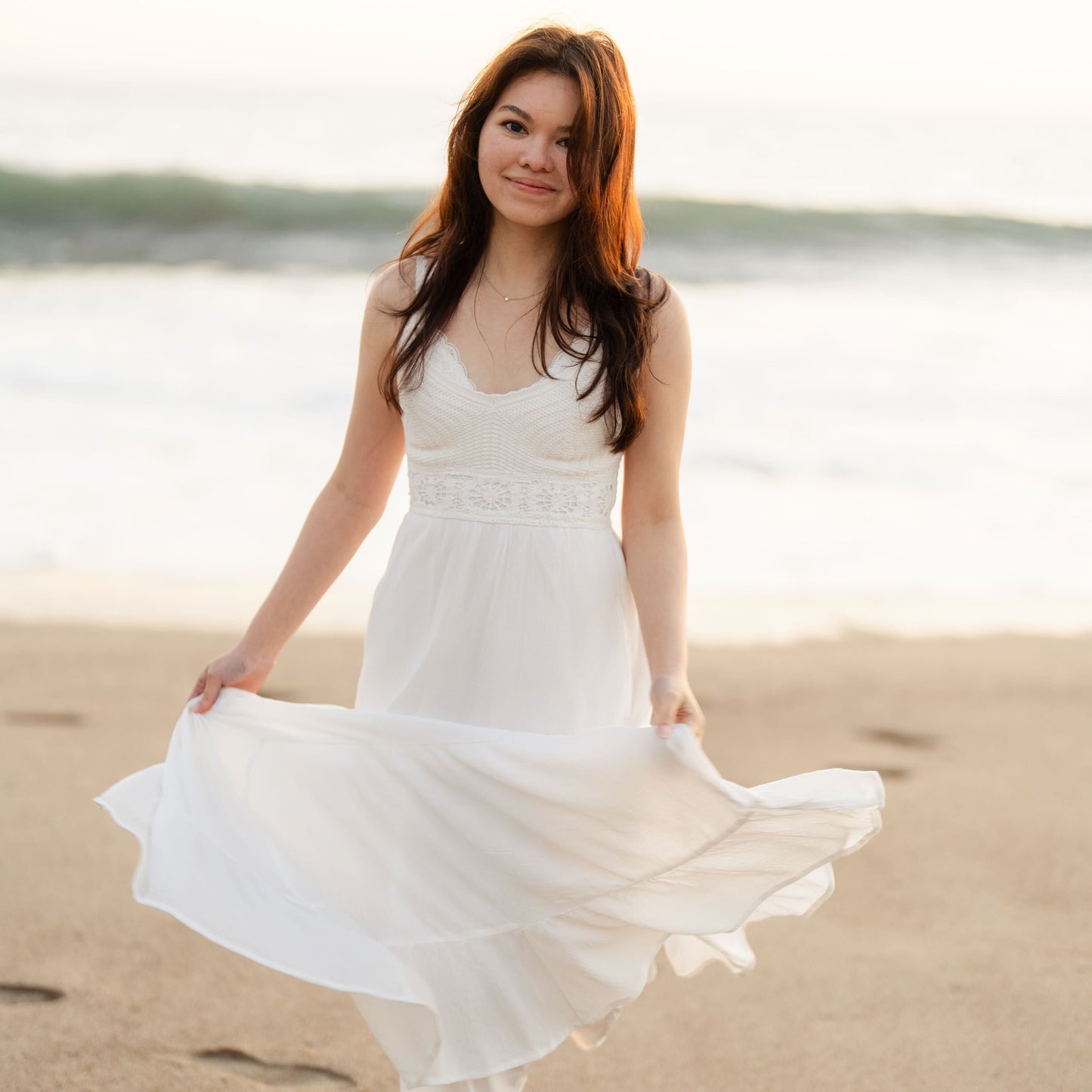 Mahal Morocco founder in a white dress standing on a beach with water in the background
